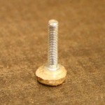 Screw with off-center brass disc